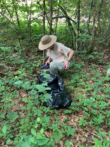 volunteer picking up trash in the forest
