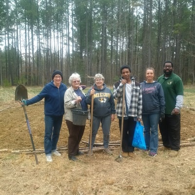 volunteers posed outdoors with gardening tools